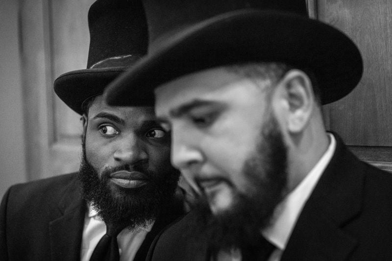 Funeral attendants Justin Mayes (left) and Preston Hall watch the service of Julian Reeder. Their top hats are an element of a Willie Watkins “signature” service that families can order to add another level of formality to a homegoing. “I wanted to do something to honor [Julian] in the most high way that we could,” says Tova Reeder.