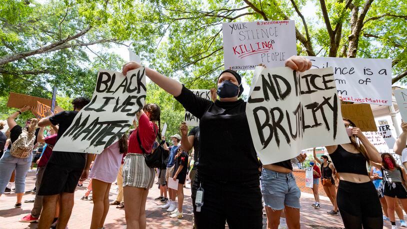 A protester holds two signs during a protest on the square over the recent Minneapolis police killing of George Floyd, held Wednesday, June 3, 2020, in Marietta, Ga. JOHN AMIS FOR THE ATLANTA JOURNAL-CONSTITUTION