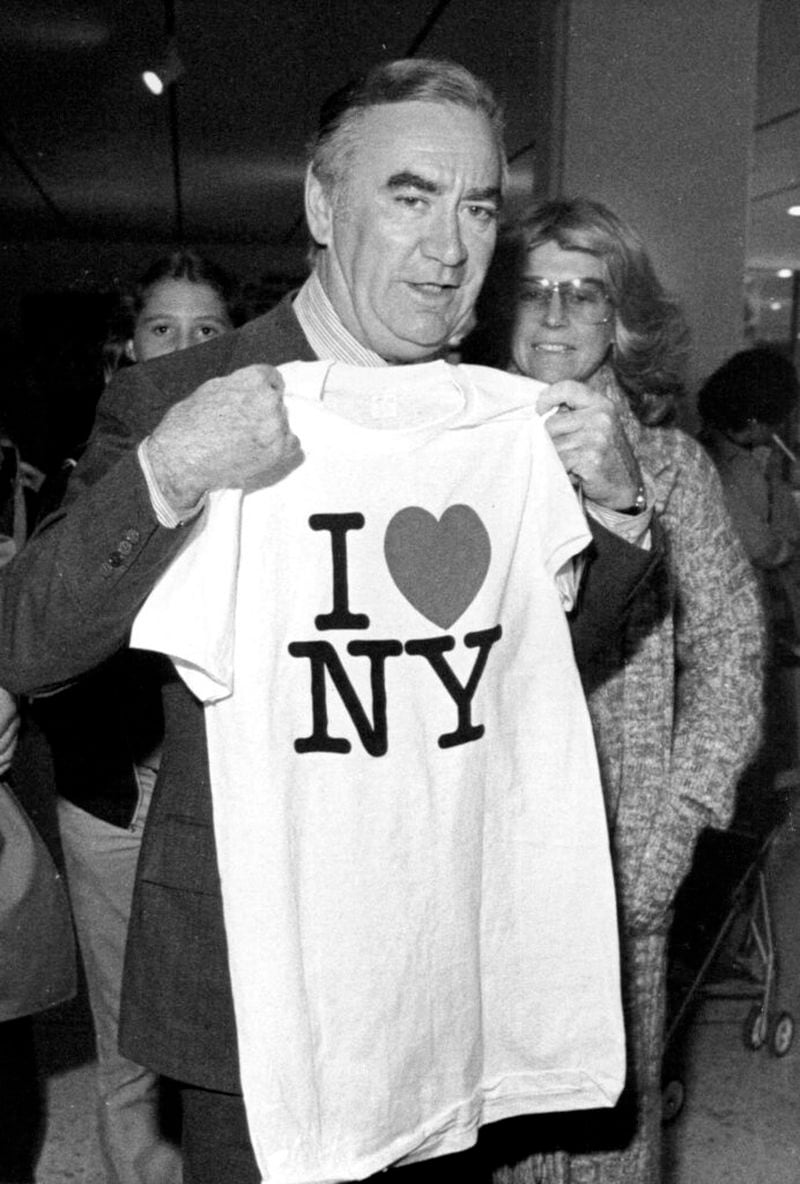 FILE - In this Oct. 9, 1977 file photo, New York Gov. Hugh Carey holds up an "I Love New York" t-shirt during the "I Love New York Fall Festival" in Albany's South Mall.  Milton Glaser, the designer who created the "I (HEART) NY" logo and the famous Bob Dylan poster with psychedelic hair, has died. He died Friday, his 91st birthday. (AP Photo, File)