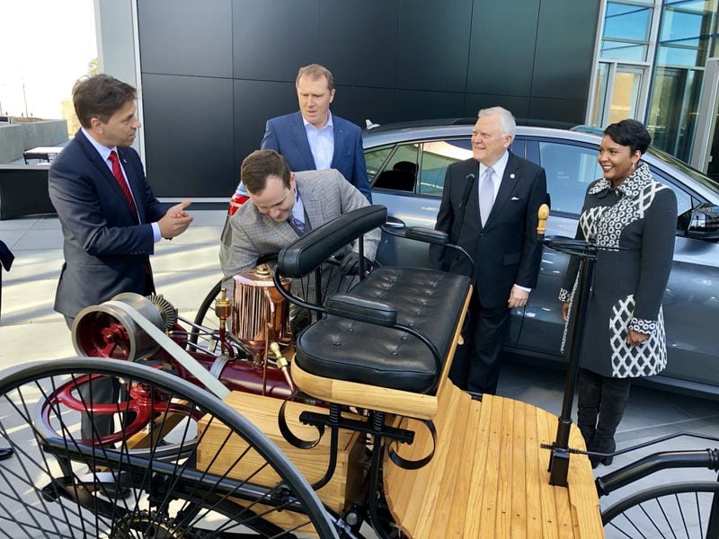 Dietmar Exler, left, CEO of Mercedes-Benz USA, shows off an original 1886 Benz Patent Motor Car, during the grand opening event at the German auto giant’s new North American headquarters in Sandy Springs. Exler is joined by Axel Harries, Mercedes vice president of product management and sales, third from left; Gov. Nathan Deal and Atlanta Mayor Keisha Lance Bottoms. Thursday, March 15, 2018. J. Scott Trubey/strubey@ajc.com.