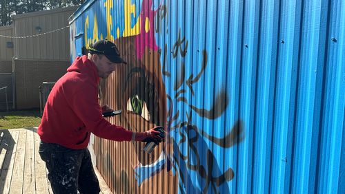 Chastain Clark, an Atlanta based muralist, designed the Dunaire C.A.F.E. Clark  enjoys helping students connect with art in different ways. Students enjoy both participating in the process of mural making and seeing themselves in the finished product, he said. Nedra Rhone/nrhone@ajc.com
