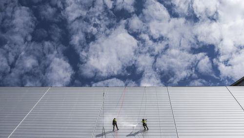 Looking lost in the clouds, workers pressure-washed the façade of Mercedes-Benz Stadium on Monday. The stadium, scheduled to open Aug. 26, will host college football’s national championship game Jan. 8. JOHN SPINK/JSPINK@AJC.COM.