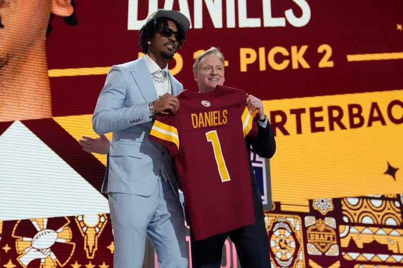 LSU quarterback Jayden Daniels poses with NFL commissioner Roger Goodell after being chosen by the Washington Commanders with the second overall pick during the first round of the NFL football draft, Thursday, April 25, 2024, in Detroit. (AP Photo/Jeff Roberson)