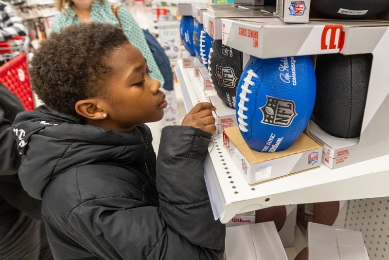 Kaleb Whidby, 9,  contemplates a football during his Shop With The Sheriff event at the Target at Atlantic Station on Saturday, December 9, 2023. (Steve Schaefer/steve.schaefer@ajc.com)