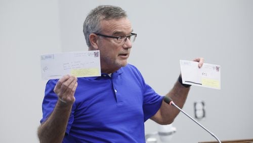 Cobb County resident Eugene Williams, who challenged the eligibility of some county voters, holds up envelopes Monday that he mailed to addresses that he says are invalid. (Natrice Miller/natrice.miller@ajc.com)