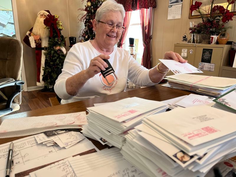 In the city hall of Santa Claus, Ga., Sue Grisham inks the city's official logo on stamped letters that locals and visitors want to send to friends and loved ones around the world. Matt Kempner / AJC