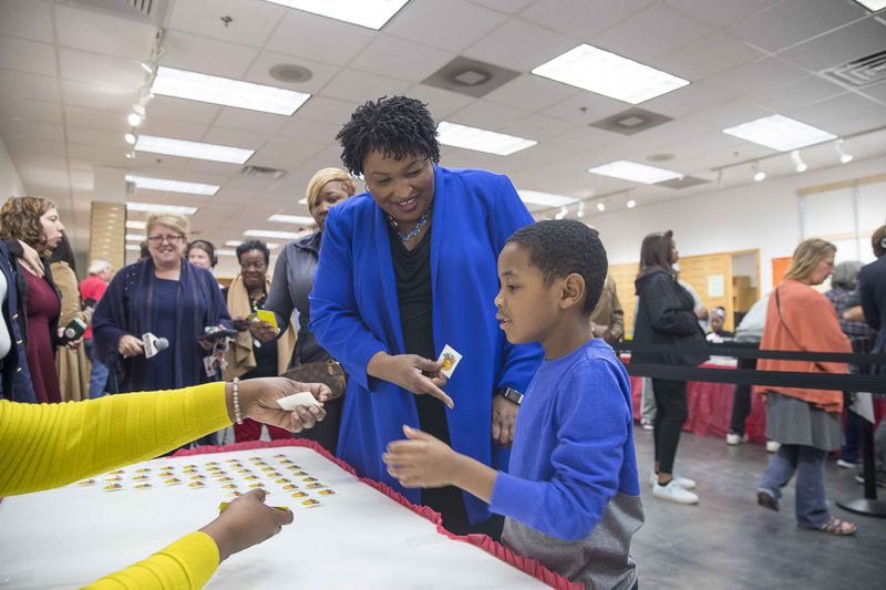 Stacey Abrams receives a voting sticker with her nephew, Cameron McLean, after casting her ballot during early voting. (ALYSSA POINTER/ALYSSA.POINTER@AJC.COM)