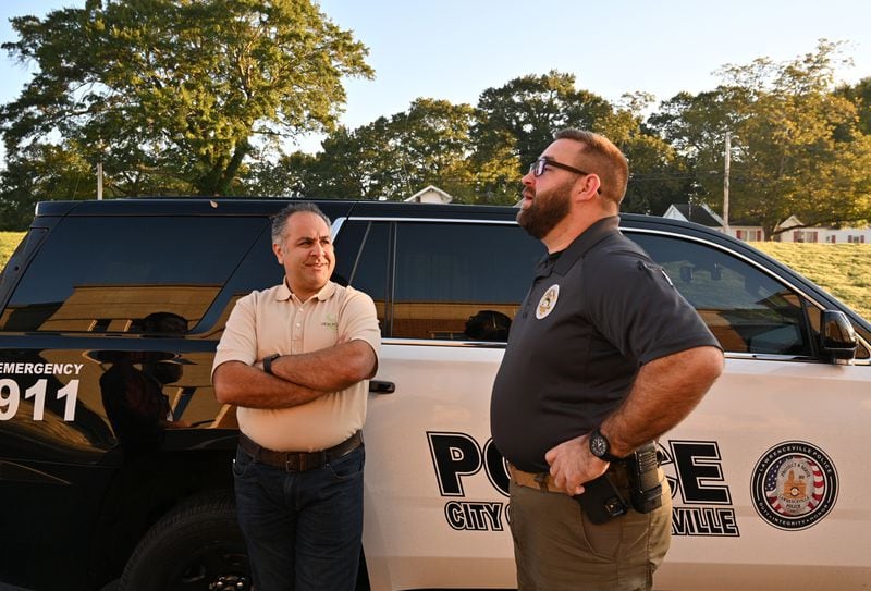 A 2021 image of Pej Mahdavi, behavioral health clinician with View Point Health talking  Officer Jacob Baird in the parking lot of the Lawrenceville Police Department. Mahdavi is one of the behavioral health clinicians who assists officers with mental health crises. (Hyosub Shin / Hyosub.Shin@ajc.com)

