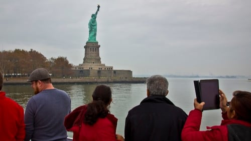 In this Nov. 5, 2015, file photo, visitors view the Statue of Liberty during a ferry ride to Liberty Island in New York. Senior White House aide Stephen Miller told reporters Wednesday, Aug. 2, 2017, that the poem written by Emma Lazarus about the "huddled masses" is not part of the original Statue of Liberty. Miller says the Statue of Liberty is a "symbol of American liberty lighting the world" and suggested the statue had little to do with immigrants. (AP Photo/Bebeto Matthews, File)