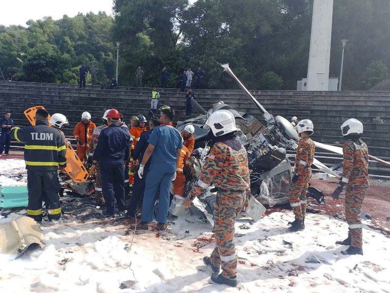 In this photo released by Fire & Rescue Department of Malaysia, fire and rescue department inspect the crash site of two helicopter in Lumur, Perak state, Monday, April 23, 2024. Malaysia's navy says two military helicopters collided and crashed during a training session, killing all 10 people on board. (Terence Tan/Ministry of Communications and Information via AP)