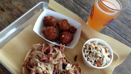 Pulled pork, Hoppin' John, hush puppies and a cold beer from Southern Soul Barbeque in St. Simons. / SUZANNE VAN ATTEN / SVANATTEN@AJC.COM