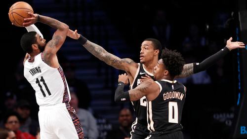 Brooklyn guard Kyrie Irving (11) passes as he is double teamed by Hawks forward John Collins (20) and guard Brandon Goodwin (0) during the first half Sunday, Jan. 12, 2020, in New York. It was Irving's first game in more than two months.