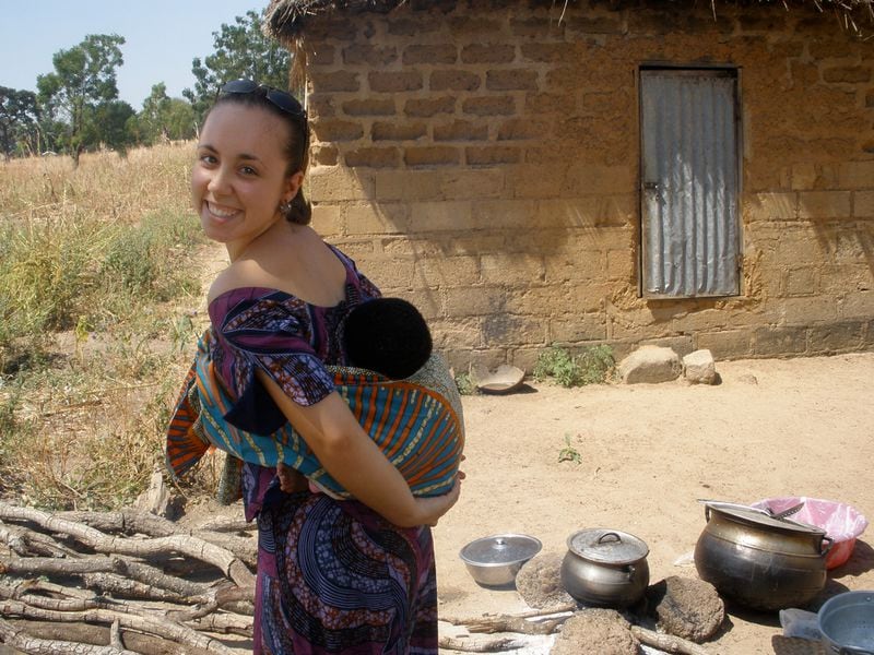 Catherine "Kate" Puzey, of Cumming, Ga., shown here in 2008 with a neighbor's child in a sling on her back. Puzey was found dead outside her home in Benin after reporting a suspected criminal to Peace Corps officials. (AP Photo/courtesy of the Puzey family)