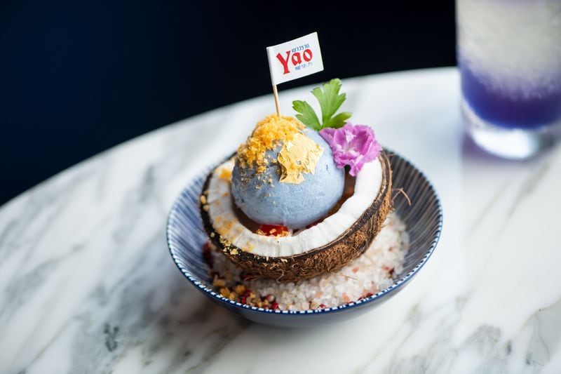 Yao's Ice Cream with butterfly pea coconut ice cream, young coconut shell, roasted peanuts, and salted egg yolk. (Mia Yakel for The Atlanta Journal-Constitution)