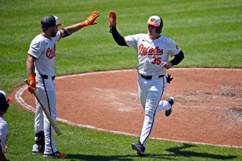 Baltimore Orioles' Adley Rutschman (35) is greeted by Anthony Santander, left, after he scored on a single by Ryan Mountcastle during the fifth inning of a baseball game against the New York Yankees, Thursday, May 2, 2024, in Baltimore. (AP Photo/Nick Wass)