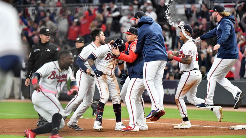 Braves players celebrate with leftfielder Eddie Rosario (center) after Rosario had the game-winning hit that scored shortstop Dansby Swanson in the ninth inning of Game 2 of the NLCS Sunday Oct. 17, 2021, against the Los Angeles Dodgers at Truist Park in Atlanta. The Braves won 5-4 to take a 2-0 series lead. (Hyosub Shin / Hyosub.Shin@ajc.com)
