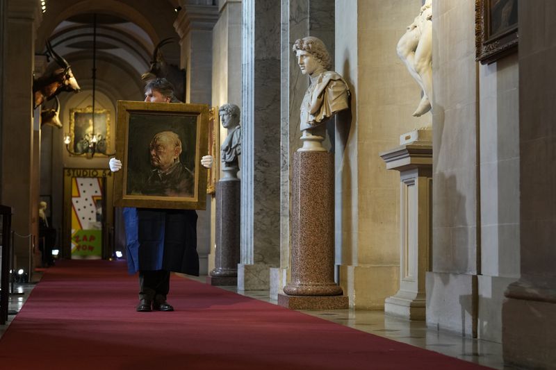 A member of staff from Sotheby's poses for the media with a portrait of the iconic former British Prime Minister Winston Churchill, painted by Graham Sutherland in 1954, at Blenheim Palace, Woodstock, England, Tuesday, April 16, 2024. The portrait will be sold at auction on June 6 with an estimated price of 500-800,000 pounds sterling (US621, 000-1,000,000). Churchill was born at Blenheim Palace on Nov. 30, 1874. (AP Photo/Alastair Grant)