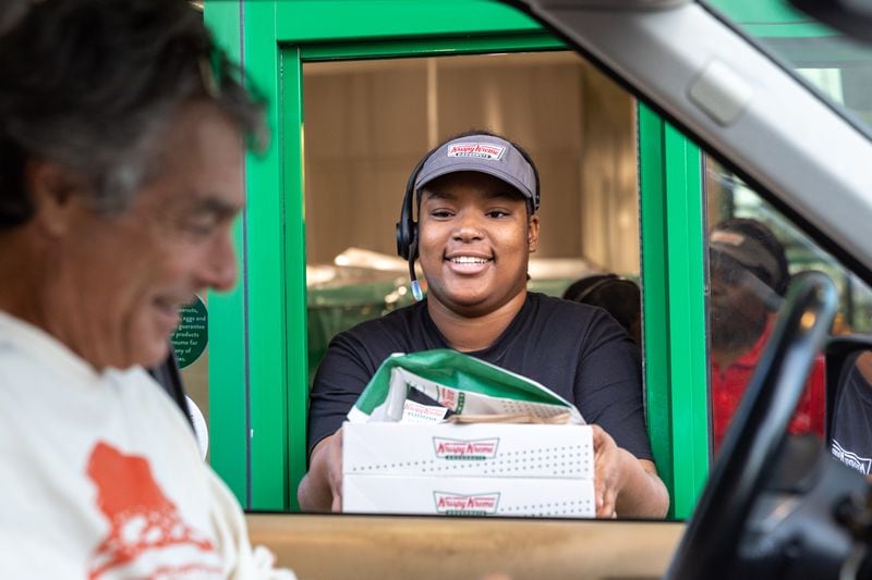 Robyn Williams serves a drive-thru customer during the grand reopening of Krispy Kreme on Ponce De Leon Avenue. (Arvin Temkar / arvin.temkar@ajc.com)