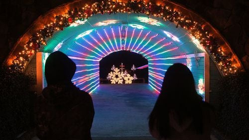 A pair of visitors take in the festive light display in a tunnel at Margaritaville in Lanier Islands in Buford. Curtis Compton/ccompton@ajc.com