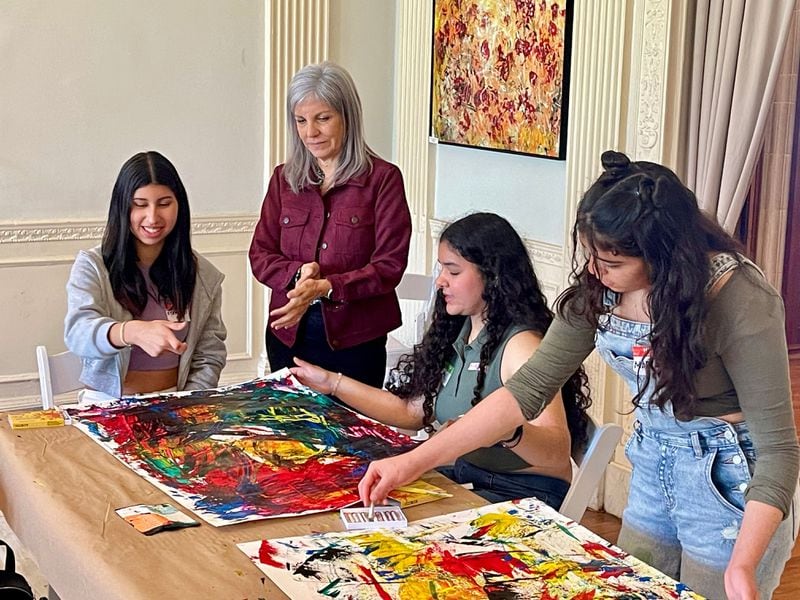Callanwolde Fine Arts Center’s Expressions program provides a half-day immersion in art, music, and movement for students who have been in the United States for less than a year and have limited English proficiency. ESOL teacher Ingrid Blum, standing, helps some of her students with their paintings. Photo courtesy of Callanwolde Fine Arts Center.