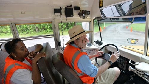 In this photo shot in 2013, Craig Anderson drives a school bus as Elena Bell supervises him on Gwinnett’s driver training course at Gwinnett County Public Schools Bus Driver Training Center in Suwanee. HYOSUB SHIN / HSHIN@AJC.COM