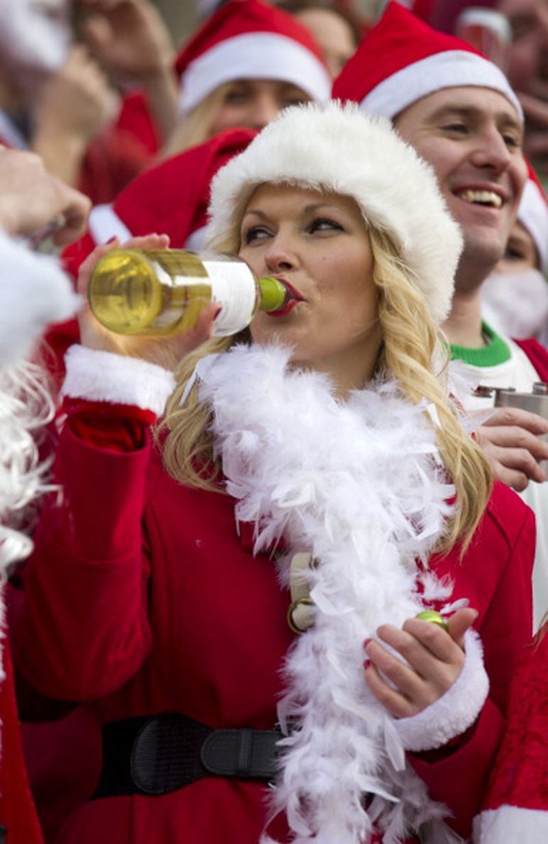A reveller in a Santa costume drinks from a bottle of wine as she takes part in the annual "Santacon" outside Saint Paul's Cathedral in central London on December 14, 2013. AFP PHOTO / JUSTIN TALLIS (Photo credit should read JUSTIN TALLIS/AFP/Getty Images)