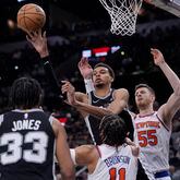 San Antonio Spurs center Victor Wembanyama, center, passes the ball over New York Knicks guard Jalen Brunson (11) during the second half of an NBA basketball game in San Antonio, Friday, March 29, 2024. (AP Photo/Eric Gay)