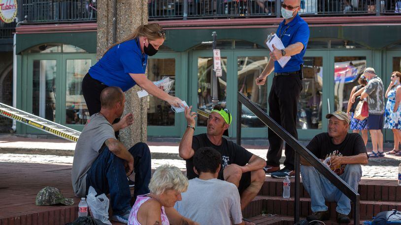 SAVANNAH, GA - Sept. 4, 2020: Members of the CoVid Resource Team, Nicole Bush, left, and Matthew Krueger, right, hand out masks to a group of people eating lunch outside.  (AJC Photo/Stephen B. Morton)