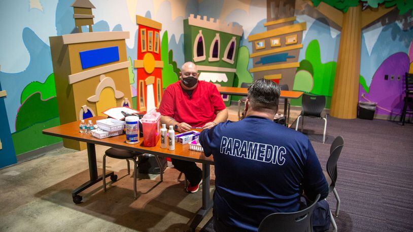 In this file photo, paramedics Jonathan Cusick and Paul Long wait for people to show up to get a COVID-19 shot in the children's room of the Impact Church in Atlanta.    STEVE SCHAEFER FOR THE ATLANTA JOURNAL-CONSTITUTION