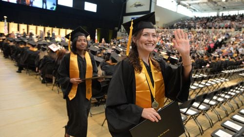 Nicole Baldwin waves to to supporters after receiving her bachelor of science degree at Kennesaw State University’s commencement in May. On Dec. 15, Kennesaw State will hold its first commencement since combining with Southern Polytechnic State University in January. More than 2,500 students are expected to graduate. BRANT SANDERLIN/BSANDERLIN@AJC.COM
