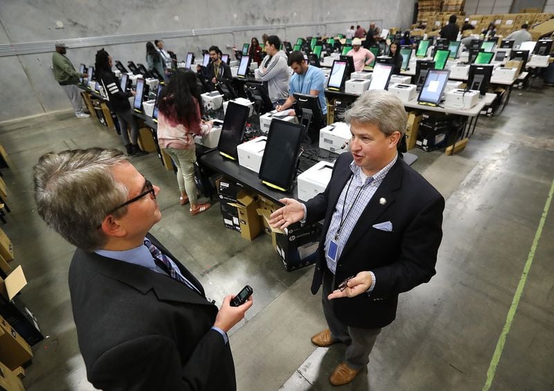 The AJC’s Mark Niesse (left) gets an inside look as the state's new voting machines are being tested and packed in an area warehouse on Tuesday, January 20, 2020, in Atlanta. CURTIS COMPTON / AJC