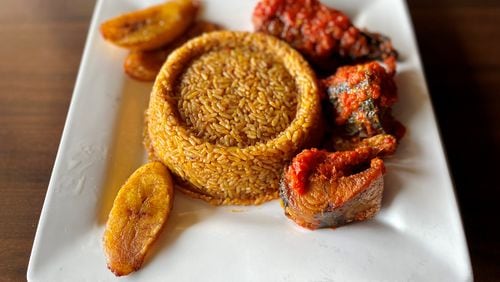 The Island Grill’s jollof rice comes with plantains and a choice of protein — in this case, fried mackerel. Wendell Brock for The Atlanta Journal-Constitution