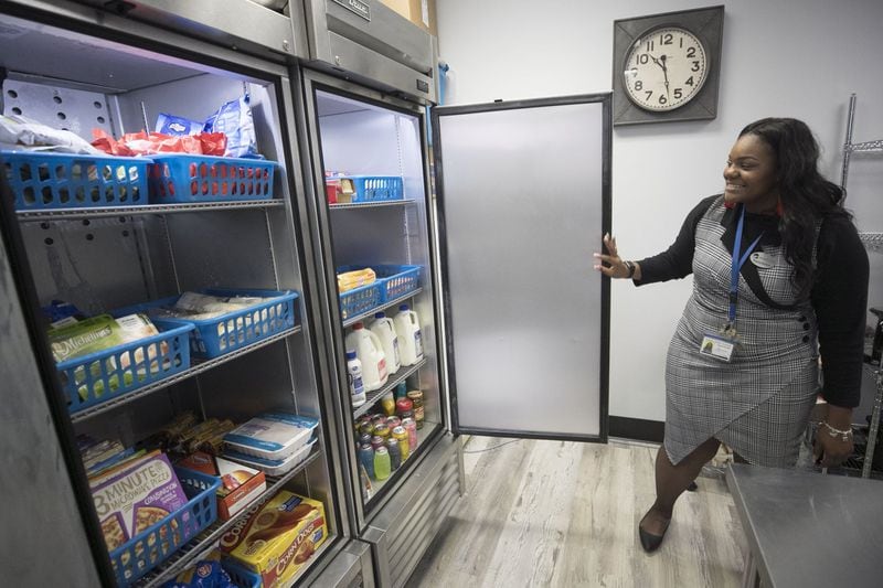 Symone Baldwin, a case manager for the nonprofit organization Wellspring Living, shows off the food pantry at Phoenix Academy on Nov. 12, 2019. Atlanta Public Schools merged its alternative high school programs into the Phoenix Academy which launched this school year. Phoenix offers a food pantry, a nursery for children of students, and a clothing boutique, where students can get needed supplies and clothes to wear to job interviews. BOB ANDRES / ROBERT.ANDRES@AJC.COM