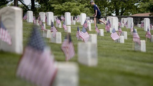 American flags are seen in front headstones as a young boy walks through Marietta National Cemetery ahead of Memorial Day 2018.