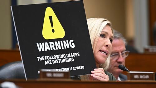 U.S. Rep. Marjorie Taylor Greene (R-Rome) holds up a warning sign during a House Committee on Oversight and Accountability hearing over the tax case against the president's son, Hunter Biden, on Capitol Hill in Washington, July 19, 2023. (Kenny Holston/The New York Times)