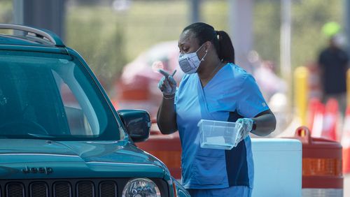 08/10/2020 - College Park, Georgia - A nurse helps an individual administer a COVID-19 test at a drive-thru COVID-19 testing clinic located in a Hartsfield-Jackson Atlanta International Airport paid parking facility in College Park, Monday, August 10, 2020. (ALYSSA POINTER / ALYSSA.POINTER@AJC.COM)