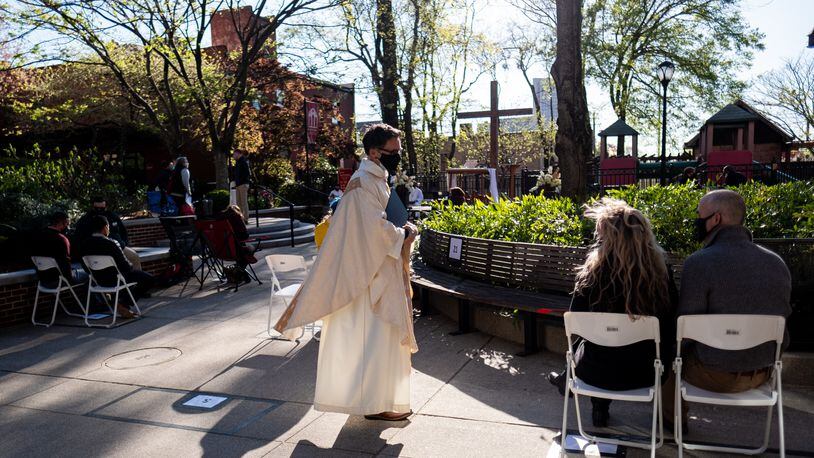 Rev. Dr. Simon J. Mainwaring talks with people before leading the outdoor Maundy Thursday service at All Saints Episcopal Church in Atlanta on April 1, 2021, in the lead up to Easter. (Ben Gray for the Atlanta Journal-Constitution)