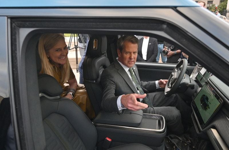 Georgia Governor Brian Kemp and First Lady Marty Kemp react as they sit inside Rivian R1T electric truck during a news conference in Atlanta on Dec 16, 2021. Kemp has been a critic of a climate law. (Hyosub Shin / Hyosub.Shin@ajc.com)