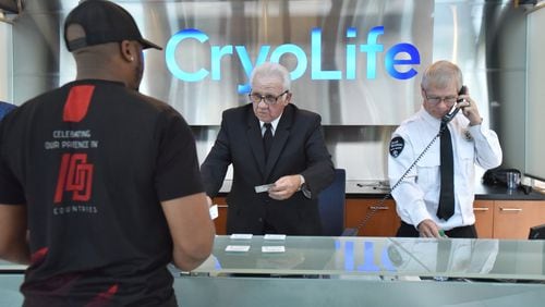 Gary Smith (center), 73, helps Darren Sligh (foreground), with checking-in as Doug Graham, security supervisor, answers a call at CryoLife, where Smith works as a security officer, in Kennesaw. Smith, 73, retired for two years but came back to work at 69, working for Allied Universal, the security company. Older workers are the fastest growing segment of the employed in Georgia and the U.S. (Hyosub Shin / Hyosub.Shin@ajc.com)