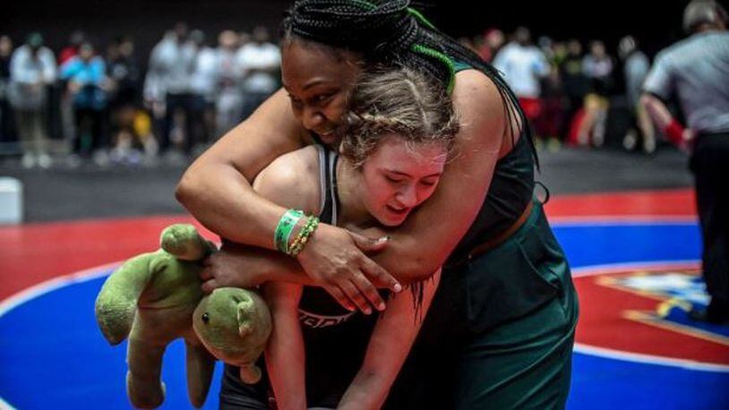 Greenbrier High School coach Coach Donell Bradley embraces Jordan Epstein after Epstein wins the semifinal match at the GHSA Girls' Wrestling Championships in February.
