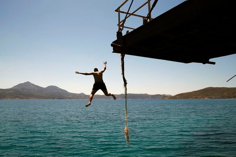 FILE - A boy dives into the sea from an old dock on the Aegean Sea island of Milos, Greece, Sunday, May 24, 2020. Greece aims to create two large marine parks as part of a 780 million euro program to protect biodiversity and marine ecosystems, with the plans to be formally announced at an international oceans conference starting in Athens Tuesday. (AP Photo/Thanassis Stavrakis, File)