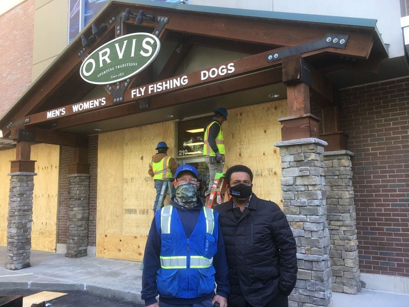 William Norwood (left) and Keevy Hood of Technique Concrete stand outside an Orvis retail store in Buckhead. A crew of six is boarding up windows at three stores today. “I’m pretty sure we’ll be doing some more,” Norwood said.