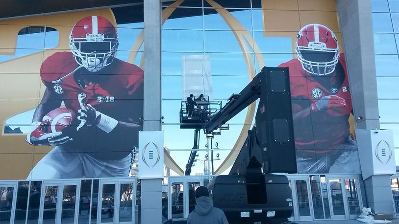 Lots of money has been spent tied to the 2018 national college football championship game in Atlanta. Much of it has been paid to out-of-town companies. Crews installed fresh images on the Mercedes-Benz Stadium on Saturday afternoon in preparation for Monday night’s game. The signs will come down soon after the game. MATT KEMPNER / AJC