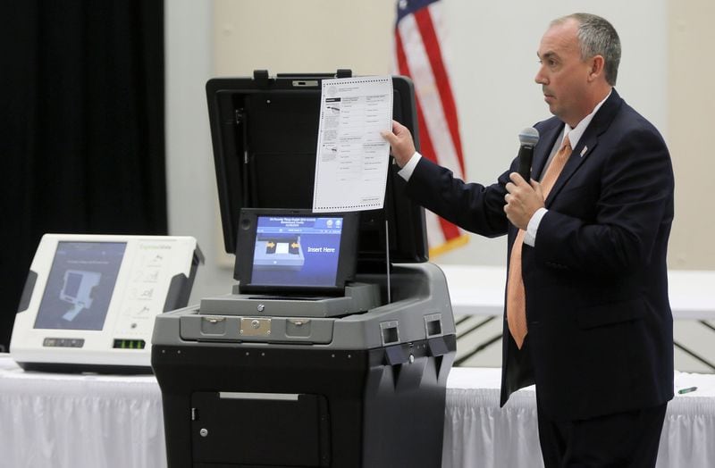 Mac Beeson from Election Systems & Software demonstrates the scanner portion of his company’s voting system during a meeting  of the state’s Secure, Accessible & Fair Elections Commission, which is which is evaluating whether to switch from electronic voting machines to ones that offer paper ballots for verification and auditing. (BOB ANDRES /BANDRES@AJC.COM)