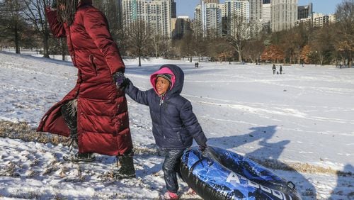 Jamila Cola and daughter, Zayna-4 head to the top of the hill with a tube at Piedmont Park on Wednesday morning, Jan. 17, 2018. Metro Atlanta schoolchildren got to enjoy a snow day, but for many, that now includes some learning time — online — in addition to the playtime outside. JOHN SPINK/JSPINK@AJC.COM