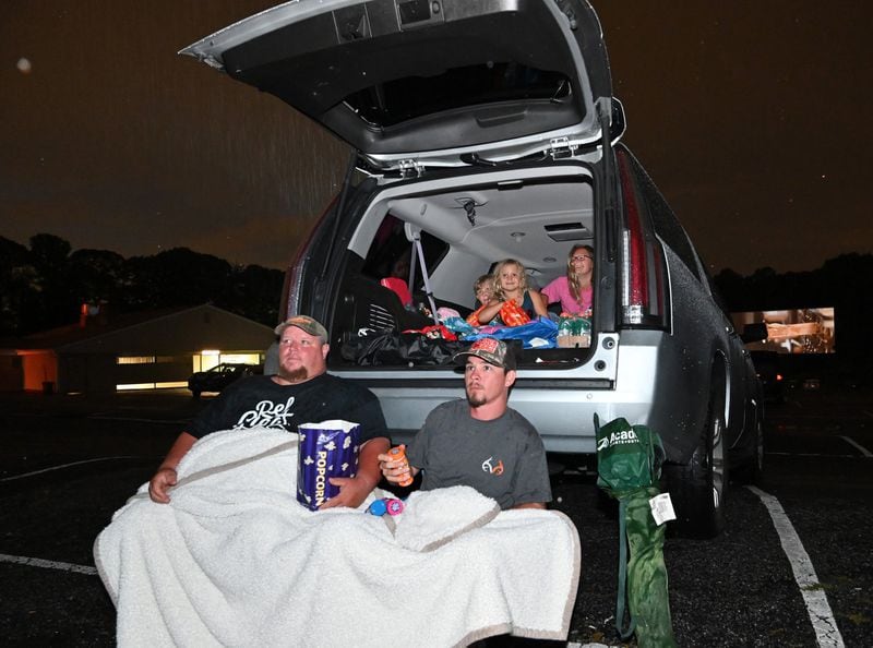 Steve Tanner (left) and Jerry Hudson join family members in watching a movie at the Starlight Drive-in on July 9. (Hyosub Shin / Hyosub.Shin@ajc.com)