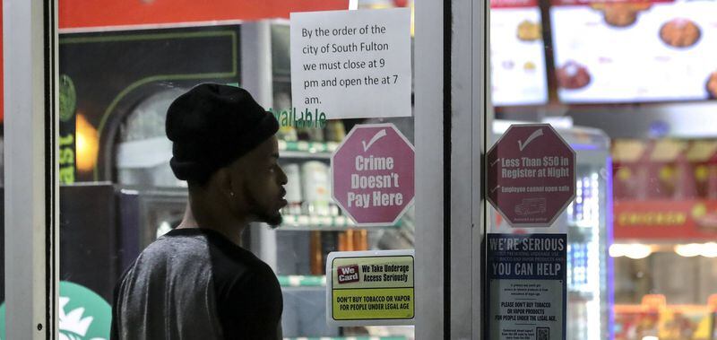 A posted sign letting customers know about the City of South Fulton’s curfew at 3515 Cascade Road on Thursday, March 19, 2020. JOHN SPINK/JSPINK@AJC.COM