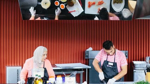 Syrian chef Majeda Nakshbandi and her son Malek Alarmash of the Clarkston-based catering business Suryana Cuisine prepared hummus and tabbouleh for the crowd at the 2017 Refugee Recipe Celebration. CONTRIBUTED BY WILLIS NORMAN