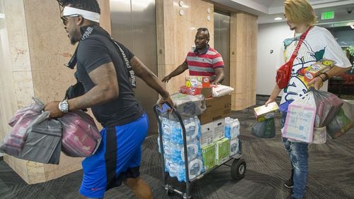 Kelson Miller (left), Stanely Babb (center) and John Abreu (right) carry donated supplies to the Bahamas Consulate in Atlanta, Tuesday, Sept. 3, 2019. The Bahamas Consulate General Atlanta is accepting emergency relief supplies for the islands in the Bahamas affected by Hurricane Dorian. ALYSSA POINTER / ALYSSA.POINTER@AJC.COM