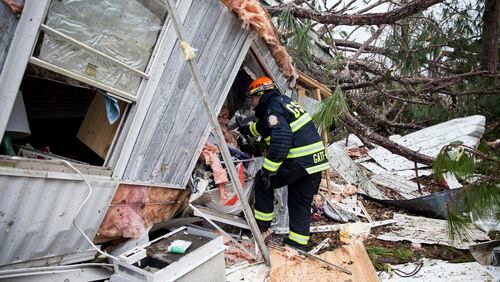 A rescue worker enters a hole in the back of a mobile home Monday, Jan. 23, 2017, in Big Pine Estates that was damaged by a tornado, in Albany, Ga. Fire and rescue crews were searching through the debris, looking for people who might have become trapped when the storm came through. (AP Photo/Branden Camp)